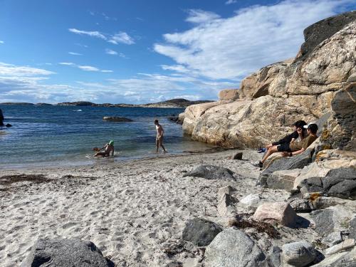 a group of people sitting on a beach at Villa Tjurpannan Grebbestad in Grebbestad