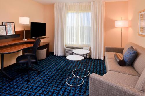 マーティンズバーグにあるFairfield Inn & Suites by Marriott Martinsburgのソファ、デスク、コンピュータが備わるホテルルームです。