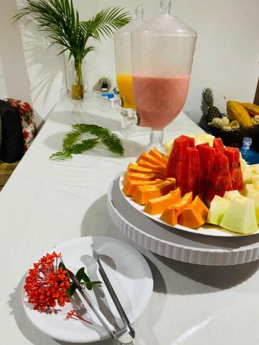 a table with a plate of fruit and a drink at Pousada Ponta da Baleia in Barra Grande