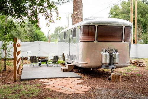 an old airstream van parked in a yard with a table and chairs at Corduroy Lodge in Pinetop-Lakeside
