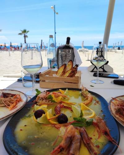 a table with a plate of food and glasses of wine at Gent's Inn Luxury in Durrës