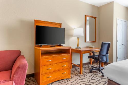 a room with a tv on a dresser with a desk at Comfort Inn & Suites Chesapeake - Portsmouth in Chesapeake