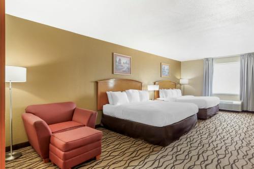 a hotel room with two beds and a chair at Comfort Inn & Suites Chesapeake - Portsmouth in Chesapeake