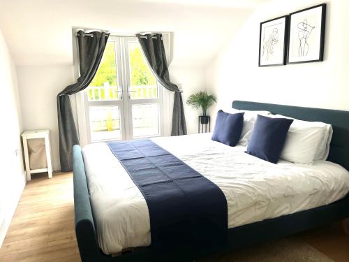 a bedroom with a blue and white bed with a window at Maidstone City Centre Penthouse Apartment in Kent