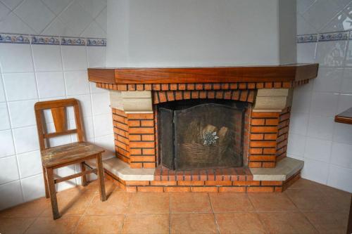 a brick fireplace in a room with a chair at Casa refúgio com pátio interior in Alcobaça