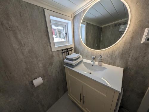 ein Bad mit einem Waschbecken und einem Spiegel in der Unterkunft Cabin magic on Senja, atmosphere like a fairytale in Botnhamn