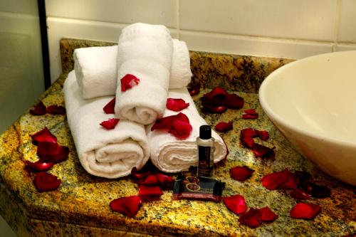 a bathroom with towels and roses on a counter at Vila Francesa Hotel in Penedo
