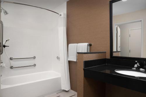 a bathroom with a sink and a tub and a mirror at Fairfield Inn & Suites By Marriott Sioux Falls Airport in Sioux Falls