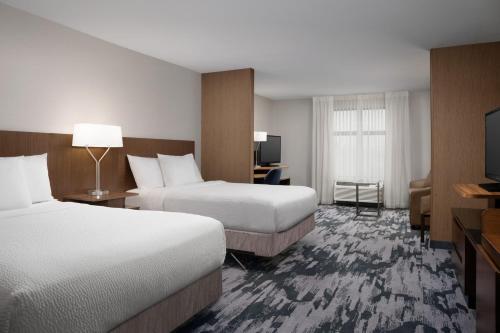a hotel room with two beds and a flat screen tv at Fairfield Inn & Suites By Marriott Sioux Falls Airport in Sioux Falls