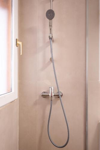 a shower with a shower head on a wall at Refugio en Albaicín y parking in Granada