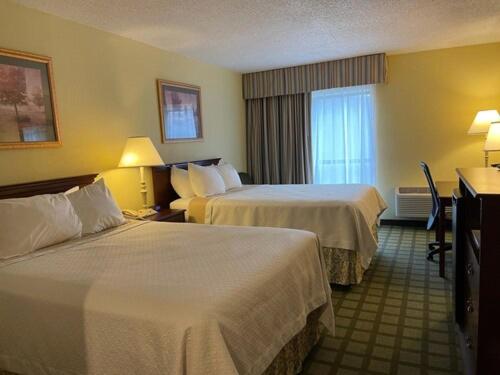 a hotel room with two beds and a desk at Days Inn & Suites by Wyndham Sutton Flatwoods in Sutton