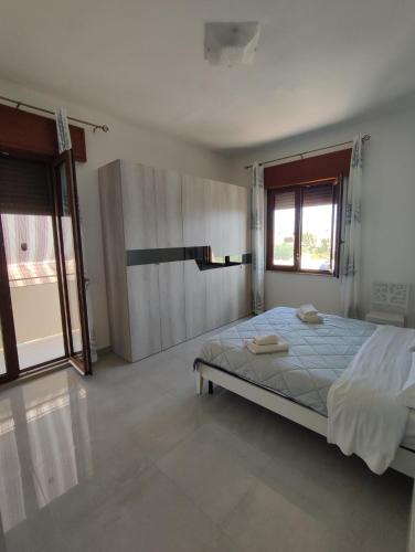 ein weißes Schlafzimmer mit einem Bett und zwei Fenstern in der Unterkunft CASA CIELO in Favignana