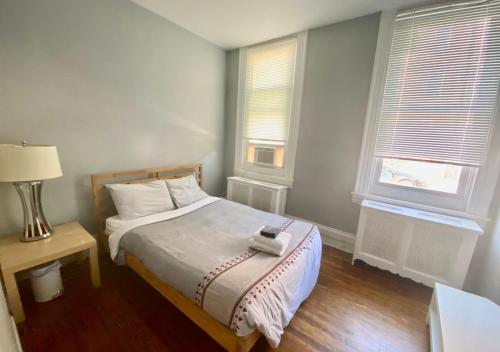 a small bedroom with a bed and two windows at Clover 2900 - Apartment and Rooms with Private Bathroom near Washington Ave South Philly in Philadelphia