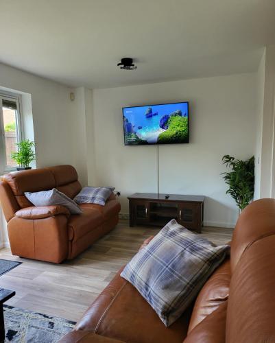a living room with two couches and a flat screen tv at Bluesea Home near Etihad in Manchester