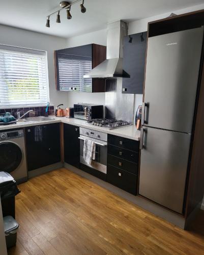 a kitchen with a stainless steel refrigerator and wooden floors at Bluesea Home near Etihad in Manchester