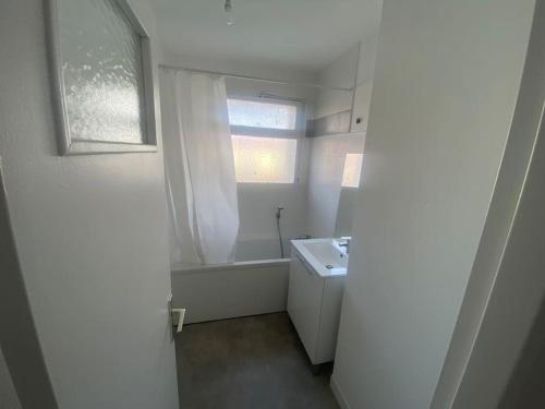 une salle de bain blanche avec un lavabo et une fenêtre dans l'établissement Mulhouse, à Mulhouse