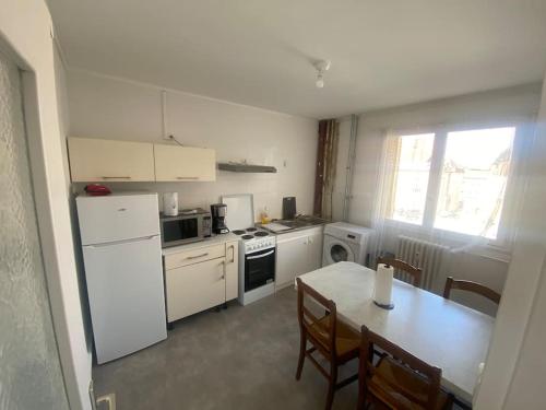 une cuisine avec des appareils blancs et une table avec des chaises dans l'établissement Mulhouse, à Mulhouse