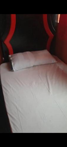 a bed with white sheets and a pillow on it at Villa Mostafa Sadek, Swimming pool, Tennis & Squash - Borg ElArab Airport Alexandria in Borg El Arab
