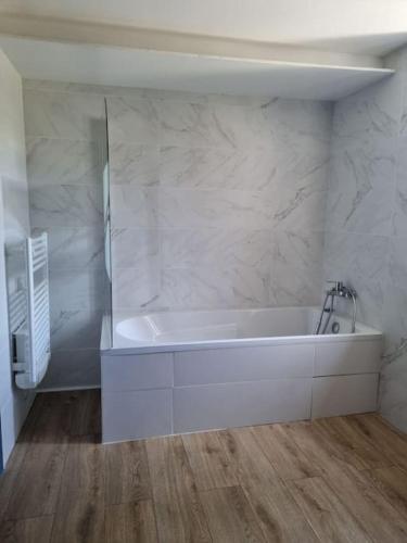 La salle de bains est pourvue d'une baignoire blanche et de murs en marbre. dans l'établissement bienvenue chez nous, à Monstéroux-Milieu