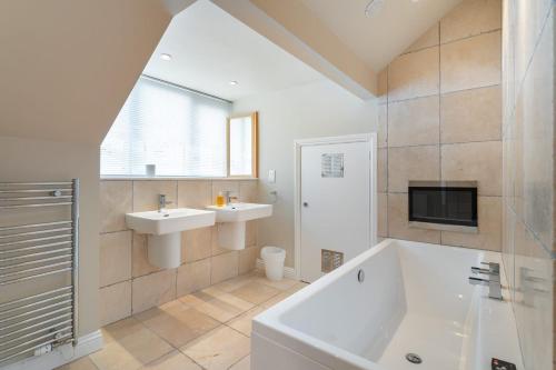 a bathroom with a tub and a sink and a tv at Ralston in Ambleside