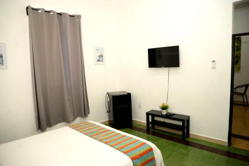Habitación de hotel con cama y TV en Hostal Mi Rincón en Santo Domingo