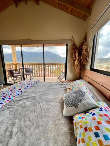 Un dormitorio con una cama grande con una ventana grande. en El ATiCO ConstanzaRD, en Constanza