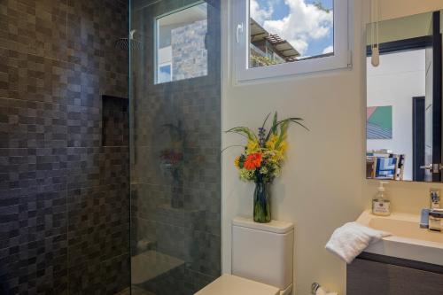 La Santa Maria Resort في سان خوان ديل سور: حمام مع دش مع إناء من الزهور على المرحاض