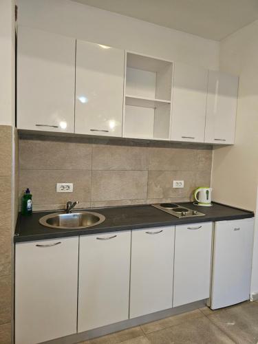 una cocina con armarios blancos y fregadero en MILENIJUM APARTMANIII, en Podgorica