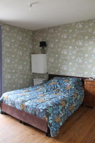 une chambre avec un lit avec un papier peint fleuri dans l'établissement Maison bourg, à Réaumur