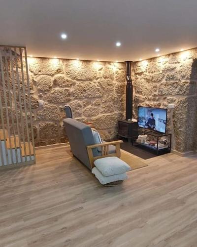 a living room with a chair and a television at Casa do Avô Xico in Sabugal
