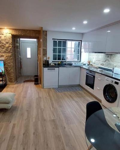a kitchen with white cabinets and a wooden floor at Casa do Avô Xico in Sabugal