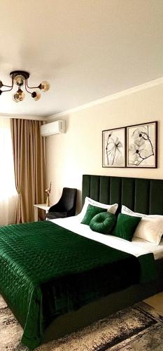 una camera da letto con un letto verde con una coperta verde di 4 you a Almaty