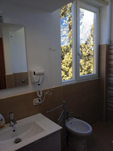 a bathroom with a sink and a toilet and a window at Bougainvillea casa vacanza in Castelbuono