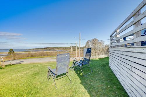 two chairs sitting in the grass next to a fence at Peaceful Lubec Home with Views Walk to Beach! in Lubec