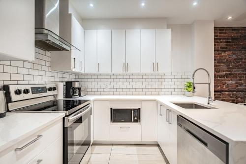 a white kitchen with white cabinets and appliances at Vibrant Le Plateau Escape for Groups Near Metro in Montréal
