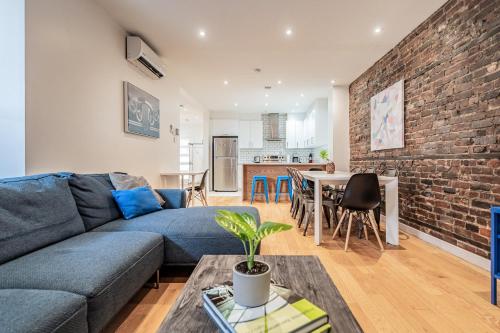 a living room with a blue couch and a brick wall at Vibrant Le Plateau Escape for Groups Near Metro in Montréal