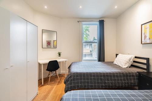 1 Schlafzimmer mit 2 Betten, einem Schreibtisch und einem Fenster in der Unterkunft Ideal Group Stay in Charming Le Plateau Near Metro in Montreal