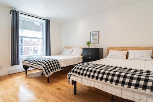 two beds in a room with a window at Vibrant Le Plateau Escape for Groups Near Metro in Montréal