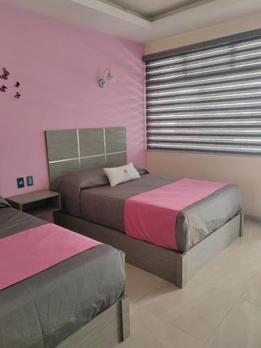 two beds in a room with pink and gray at Villa Granada in Santa Cruz Tecamac