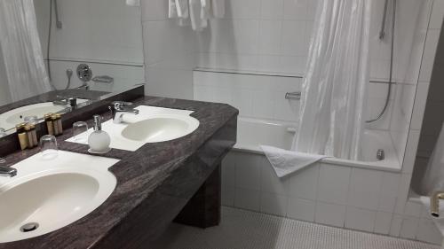 a bathroom with two sinks and a bath tub at Hotel Unger in Stuttgart