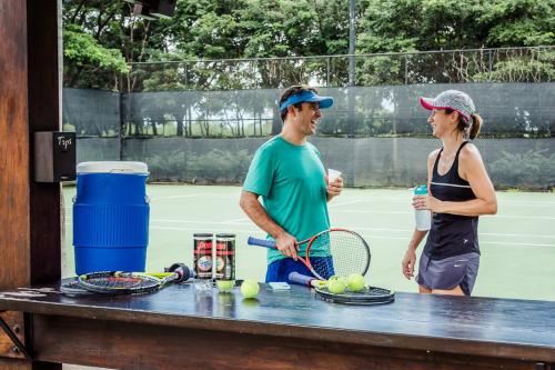 Ein Mann und eine Frau stehen auf einem Tennisplatz in der Unterkunft Luxury Vacation Rentals At Hacienda Pinilla in Tamarindo