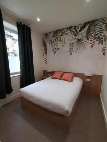 a bedroom with a bed with white sheets and plants on the wall at Bloom Hostel Bar & Garden in Bordeaux