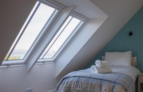 a bedroom with three windows and a bed with towels at 10 Husabost in Totaig