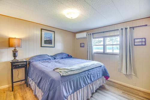 a bedroom with a blue bed and a window at Lakefront Cabin in Jay with Deck, Views and Boat Ramp! in Jay