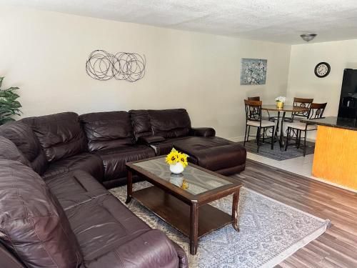 a living room with a brown leather couch and a table at Peaceful 2bed,1bath condo with free parking all yours to enjoy in Fresno