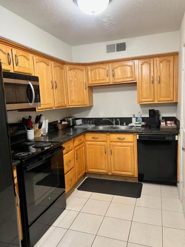 a kitchen with wooden cabinets and black appliances at Peaceful 2bed,1bath condo with free parking all yours to enjoy in Fresno