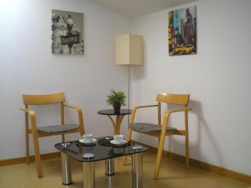 Habitación con 2 sillas, mesa y lámpara en Apartamentos Zaragoza Centro, en Zaragoza