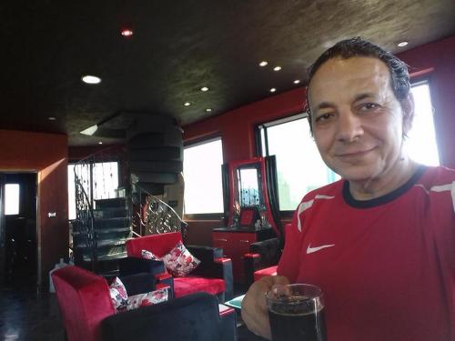 un hombre sosteniendo un vaso de cerveza en un restaurante en Villa Mostafa Sadek, Swimming pool, Tennis & Squash - Borg ElArab Airport Alexandria, en Borg El Arab