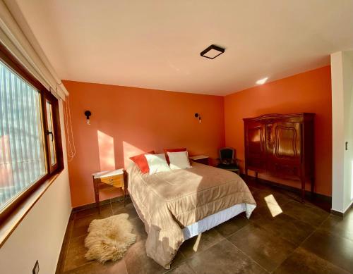 a bedroom with orange walls and a bed and a window at Bosques de ñires in Ushuaia