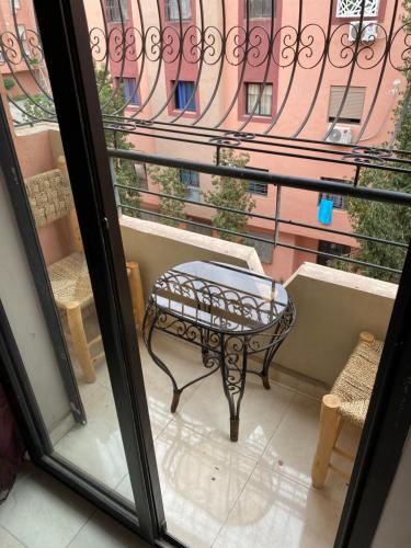 balcón con mesa, sillas y ventana en Appartement Marrakech, en Marrakech